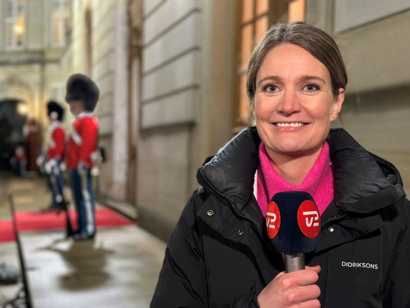 Foto af Marie Rønde foran Amalienborg. To gardere skimtes i baggrunden.n