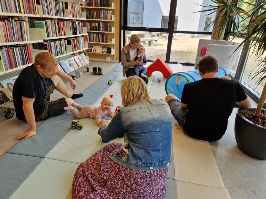 Fædre med småbørn leger på gulvet i biblioteket